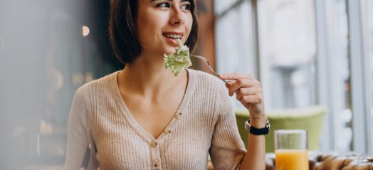 Young woman eating healthy breakfast with juice in a cafe